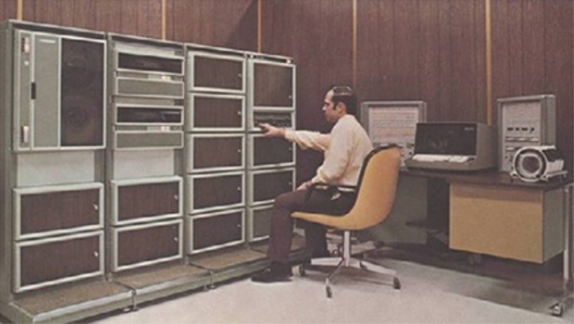 Man working with tape decks on a computer in the 1970's